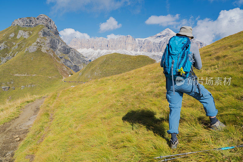 在意大利北部Dolomites的Viel dal Pan小径上休息时，老妇人享受萨斯·德·卡佩罗峰的美丽景色。